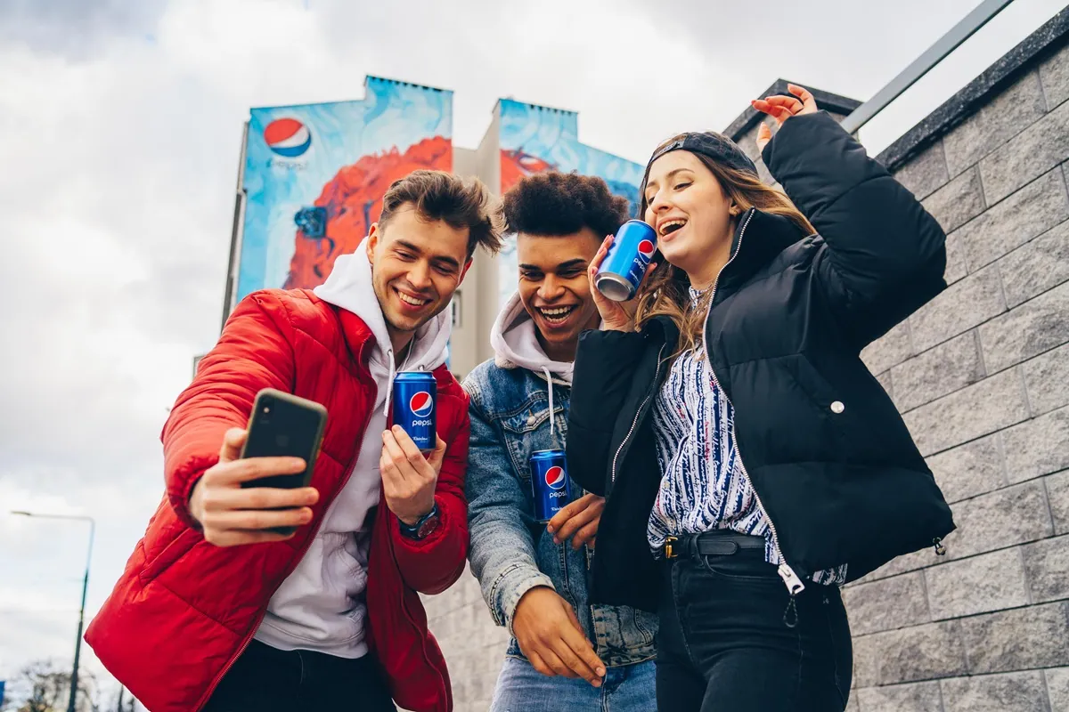 Grupa przyjaciół trzymająca skarpetki pepsi w puszce i robiąca sobie selfie.